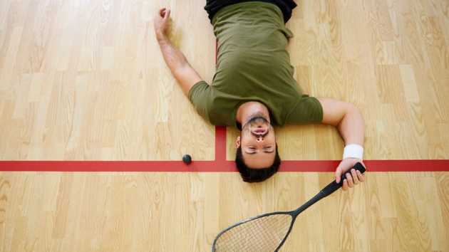 Squash-Spieler liegt auf dem Boden