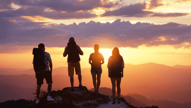 Menschen stehen auf einem Berggipfel und bewundern die Landschaft